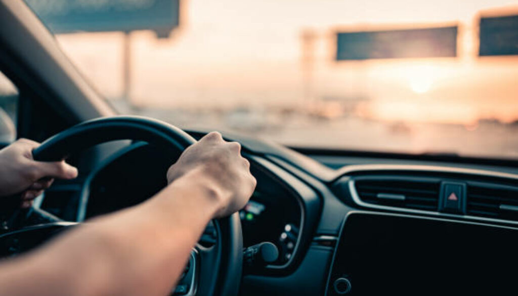 Close-up - Hand of man driving car on the road.